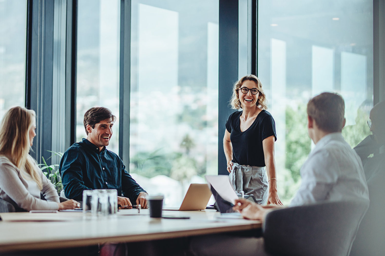 Office colleagues having casual discussion during meeting in conference room. Group of men and women sitting in conference room and smiling.