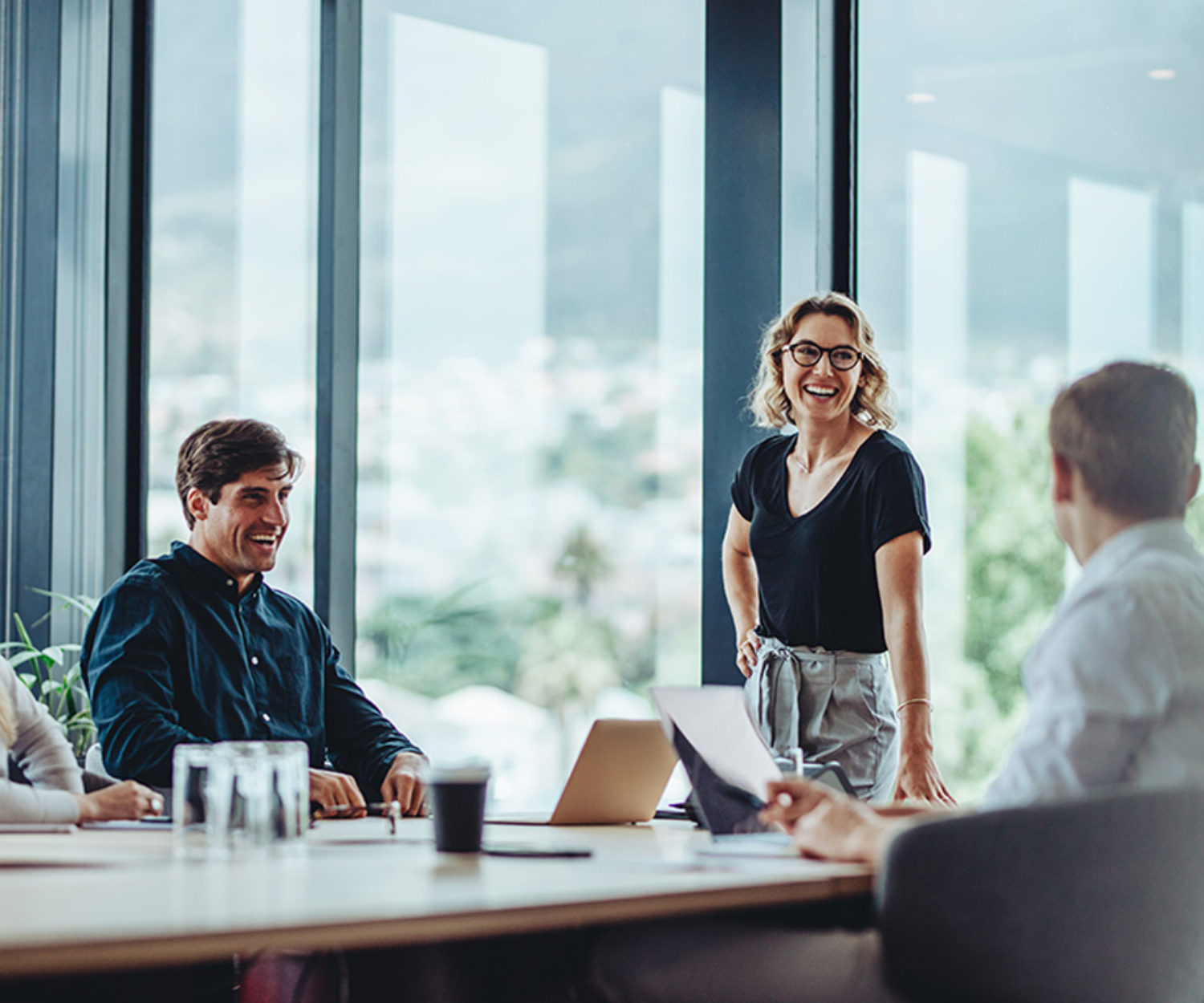Office colleagues having casual discussion during meeting in conference room. Group of men and women sitting in conference room and smiling.